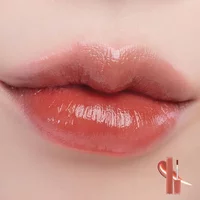 Romand Dewyful Water Tint #2 Salty Peach on lips, glossy peach hue, small tube with applicator in corner.
