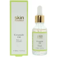 Clear glass bottle with dropper, gold cap, and green label, next to matching green box labeled "Skin Research Ceramide Oil."