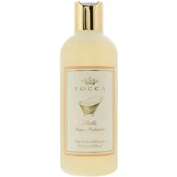 Cream-colored Tocca Stella body wash bottle with gold cap and elegant label featuring a vintage bathtub illustration.