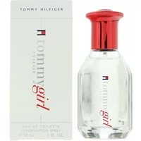 Clear glass bottle with red cap, "Tommy Girl" logo, next to white box with red and blue Tommy Hilfiger branding.