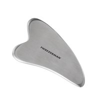 Stainless steel Tweezerman Gua Sha tool with a smooth, heart-shaped design and engraved brand name.