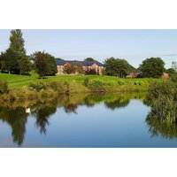 Macdonald Hill Valley Hotel with lush green golf course, serene pond, and surrounding trees under a clear blue sky.