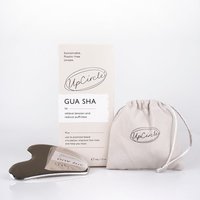 Brown UpCircle Gua Sha stone with smooth curves, beige box, and drawstring pouch.