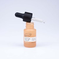 Peach-colored UpCircle Peptide Serum bottle with black dropper, labeled with custard apple and blood orange details.