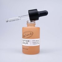 Peach-colored UpCircle Peptide Serum bottle with black dropper, labeled with custard apple and blood orange.