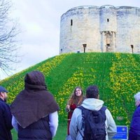 Tour guide with group at York castle mound, surrounded by daffodils, showcasing Viking history walking tour experience.