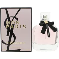 Clear glass bottle of Yves Saint Laurent Mon Paris perfume with pink liquid, black bow, and matching box.