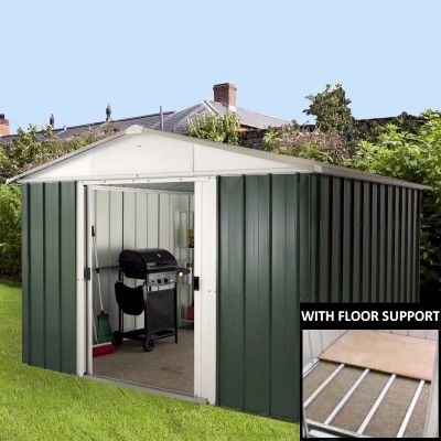 Green metal shed with a gable roof, featuring vertical panels, double doors, and a floor support system, set in a garden with greenery in the background.