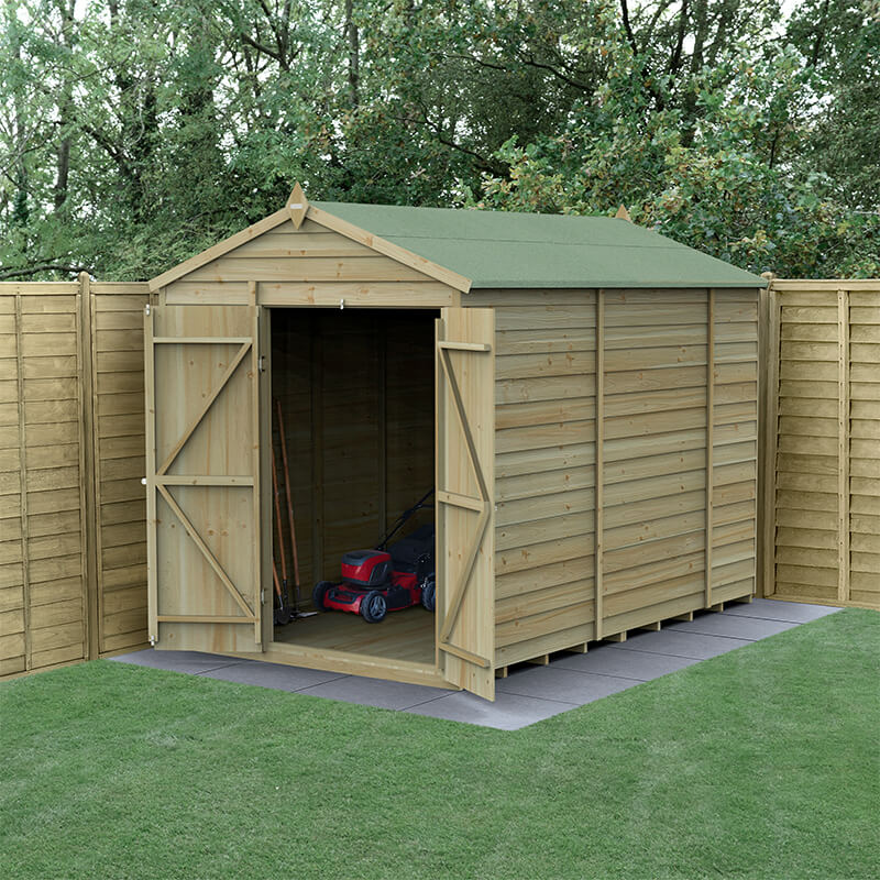 Wooden apex shed with a green felt roof, featuring double doors and a natural wood finish, set on a paved base with tools visible inside, surrounded by wooden fencing and grass.