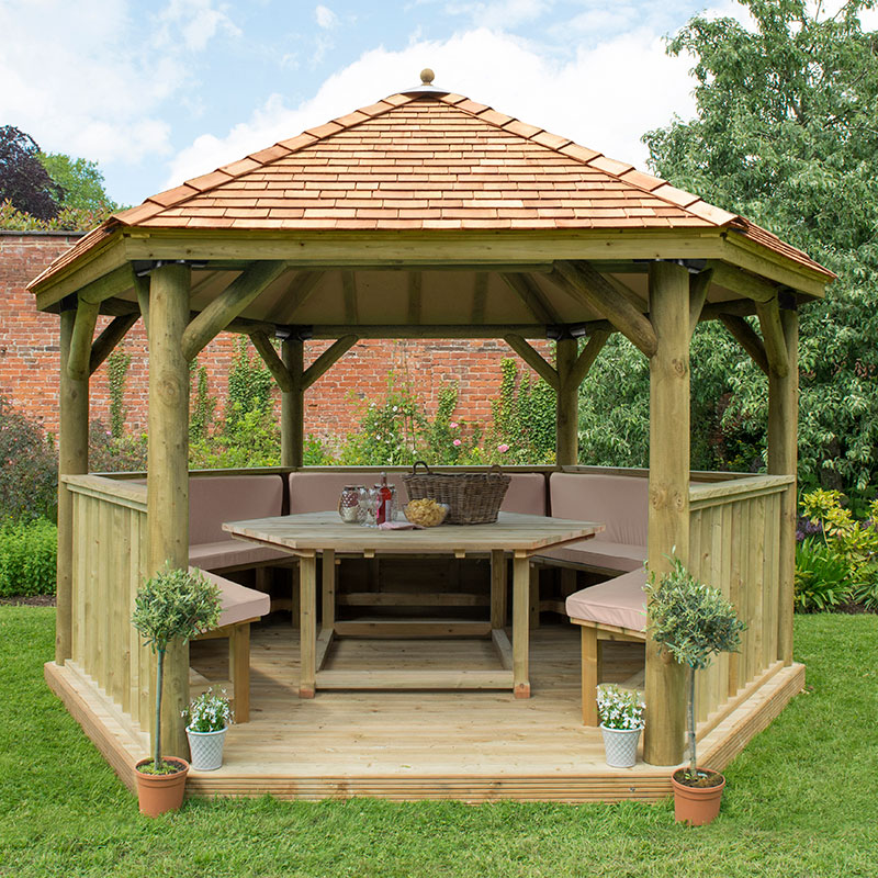 Luxury wooden garden gazebo with a New England cedar roof, featuring a spacious seating area for up to 15 people, surrounded by greenery and potted plants.