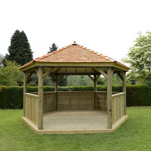 Luxury wooden gazebo with a New England cedar roof, featuring a hexagonal design, natural wood finish, and spacious seating for up to 19 people, set in a green garden.