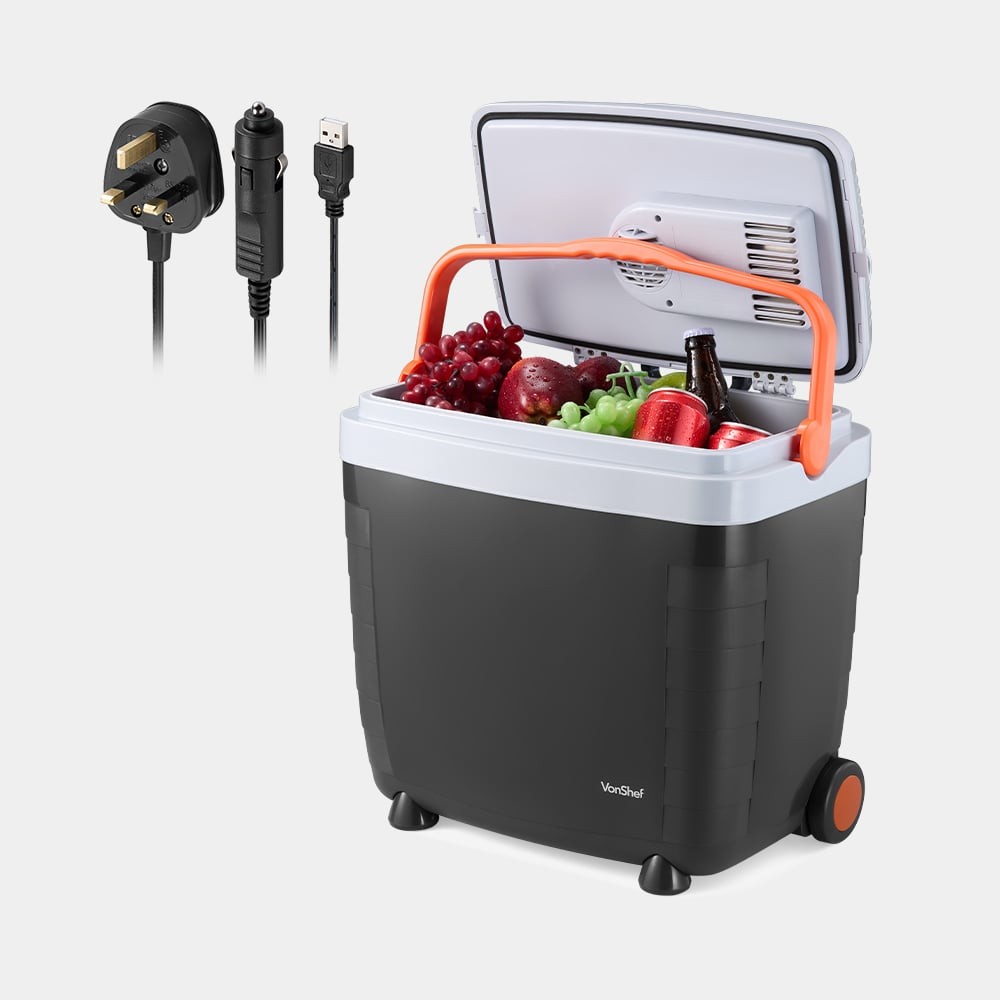 28L electric cool box on wheels by VonHaus, featuring a black body with an orange handle, a hinged lid, and filled with fruits and drinks, includes power cord and USB cable.
