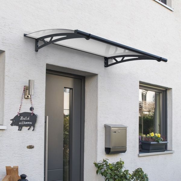 Grey door canopy with a curved design, made of durable polycarbonate and aluminum, featuring black brackets, mounted above a modern entrance with a mailbox and decorative sign.