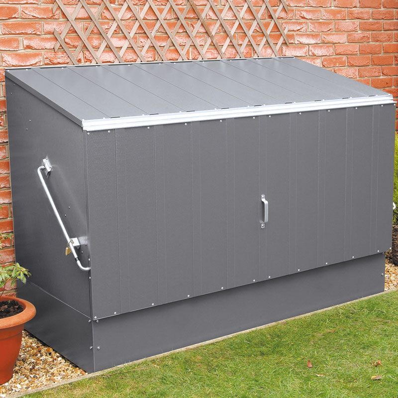 Anthracite-colored metal bike shed measuring 6'4" x 2'9", featuring a sloped roof, double doors, and a sturdy handle, set against a brick wall and garden backdrop.