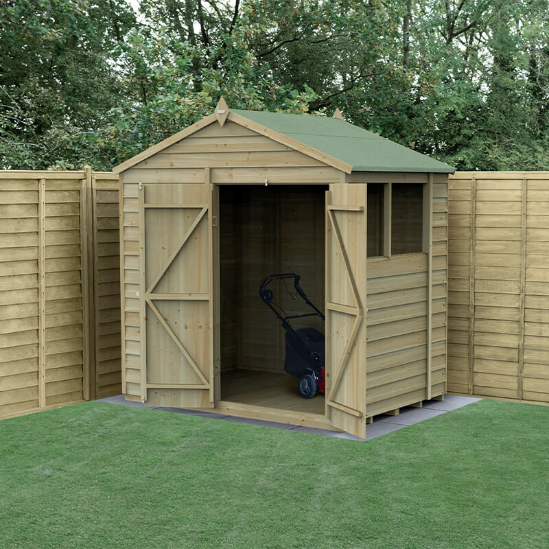 A wooden apex shed with a green felt roof, double doors, and pressure-treated timber, set on a grassy area surrounded by wooden fencing.