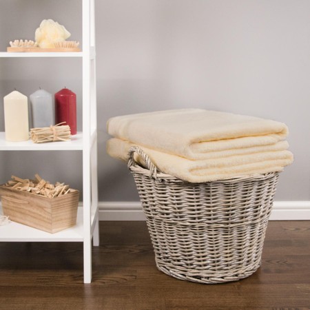 Soft cream bamboo bath sheets stacked neatly in a woven basket, showcasing their plush texture and luxurious feel, ideal for a cozy bathroom setting.
