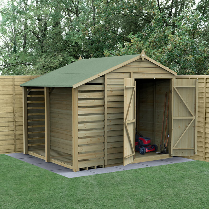 A wooden apex shed with a green felt roof, featuring double doors, pressure-treated timber, and a log store, set on a grassy area surrounded by wooden fencing.