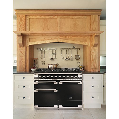 Stainless steel Rangemaster Elise 110cm dual fuel range cooker with five gas burners, two ovens, and a sleek black finish, set in a modern kitchen with wooden cabinetry.