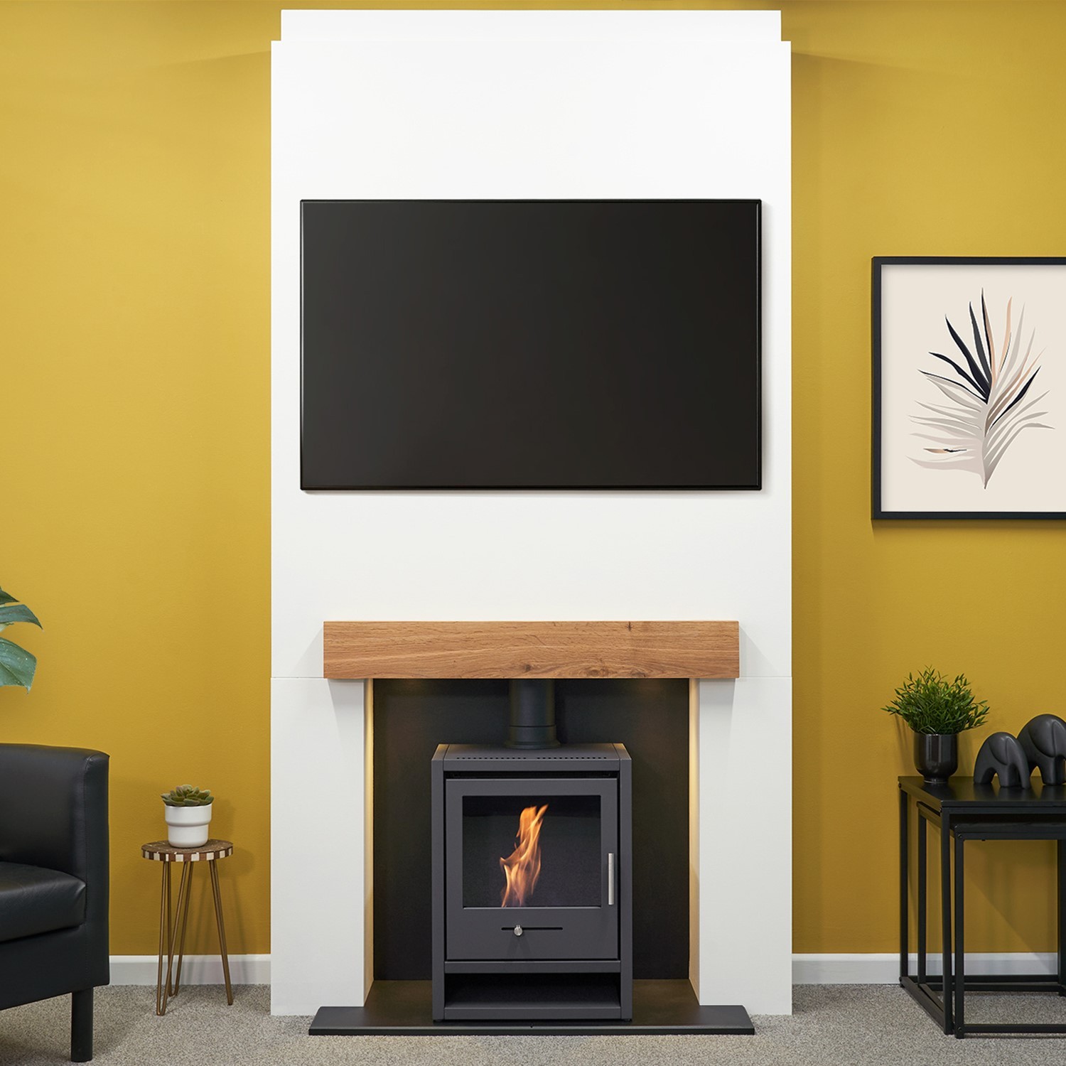 Acantha Pre-Built Stove Media Wall features a charcoal grey OKO S1 bioethanol stove, a wooden mantel, and a sleek black TV above, set against a vibrant yellow wall.