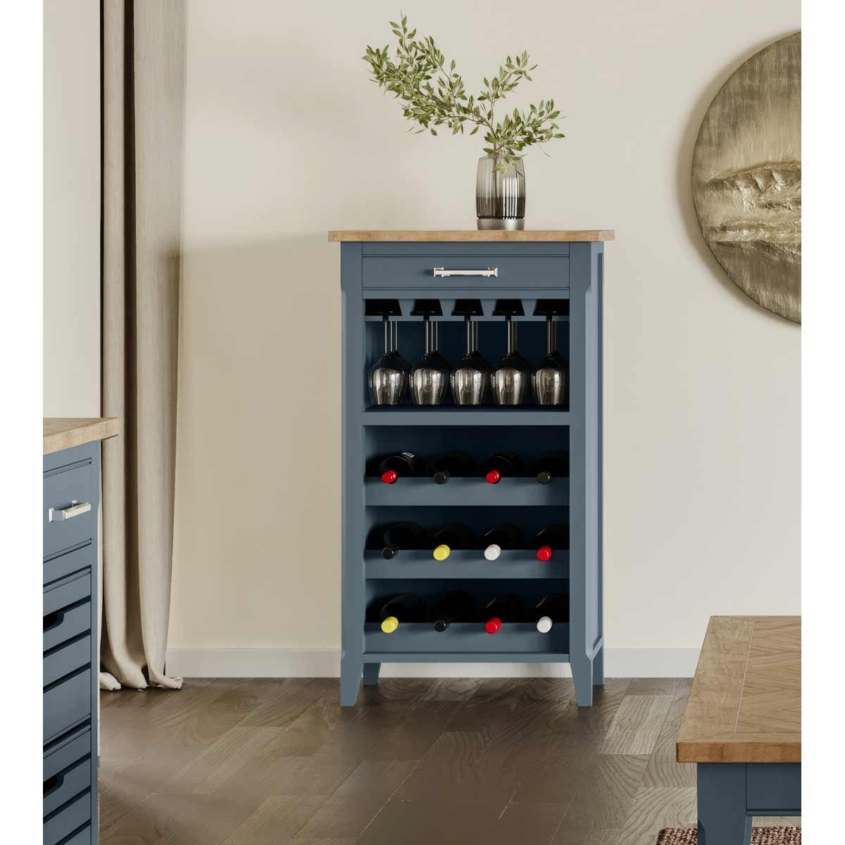Cobalt blue wine rack and glass storage cabinet featuring a wooden top, five wine slots, and space for hanging glasses, complemented by a decorative vase with greenery.
