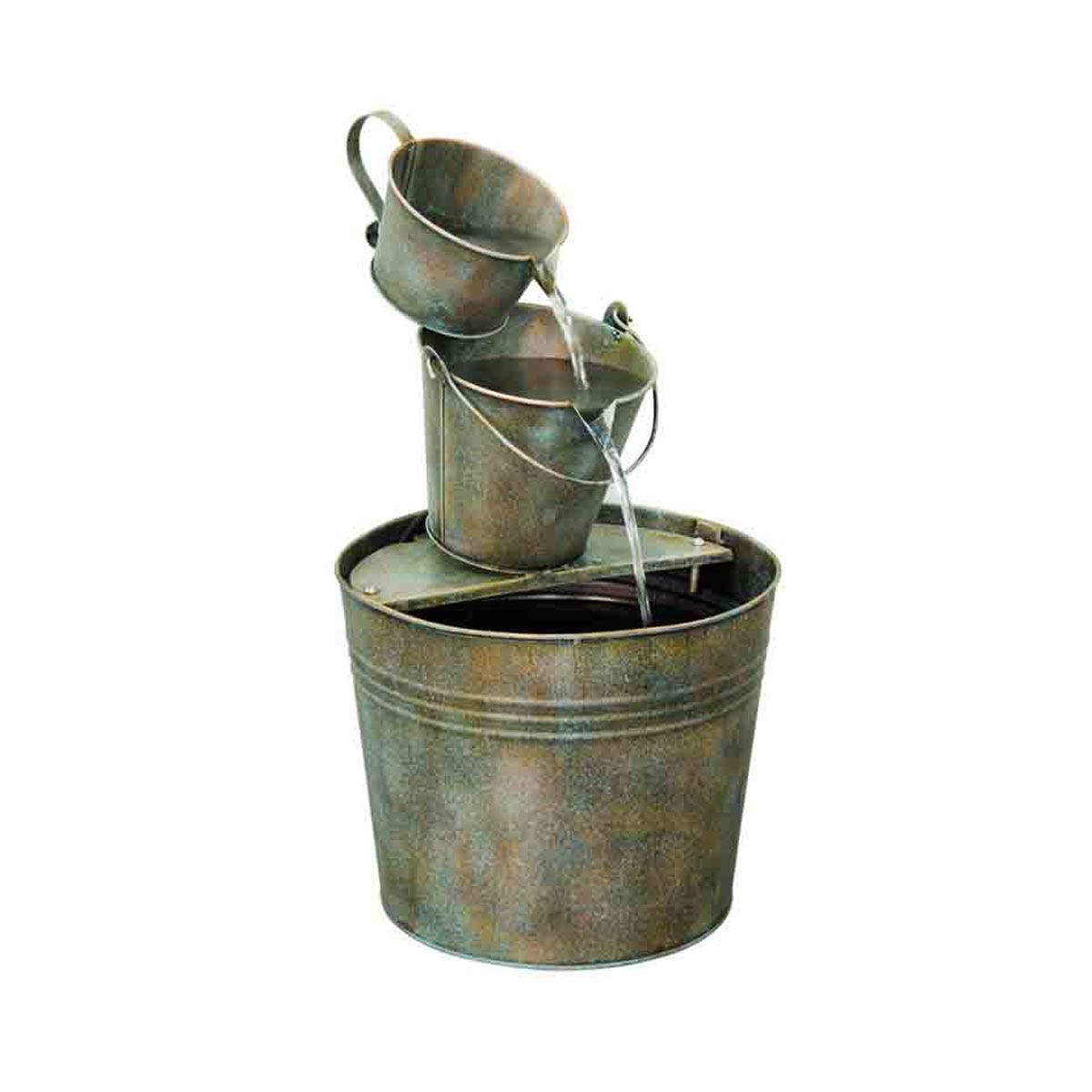A rustic metal water feature with three stacked buckets, each pouring water into the larger base bucket, showcasing a weathered, antique finish.