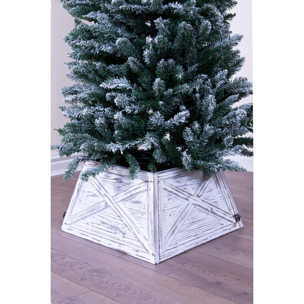 Brushed white wooden Christmas tree skirt with a geometric design, featuring a rustic finish, supporting a lush green artificial Christmas tree.
