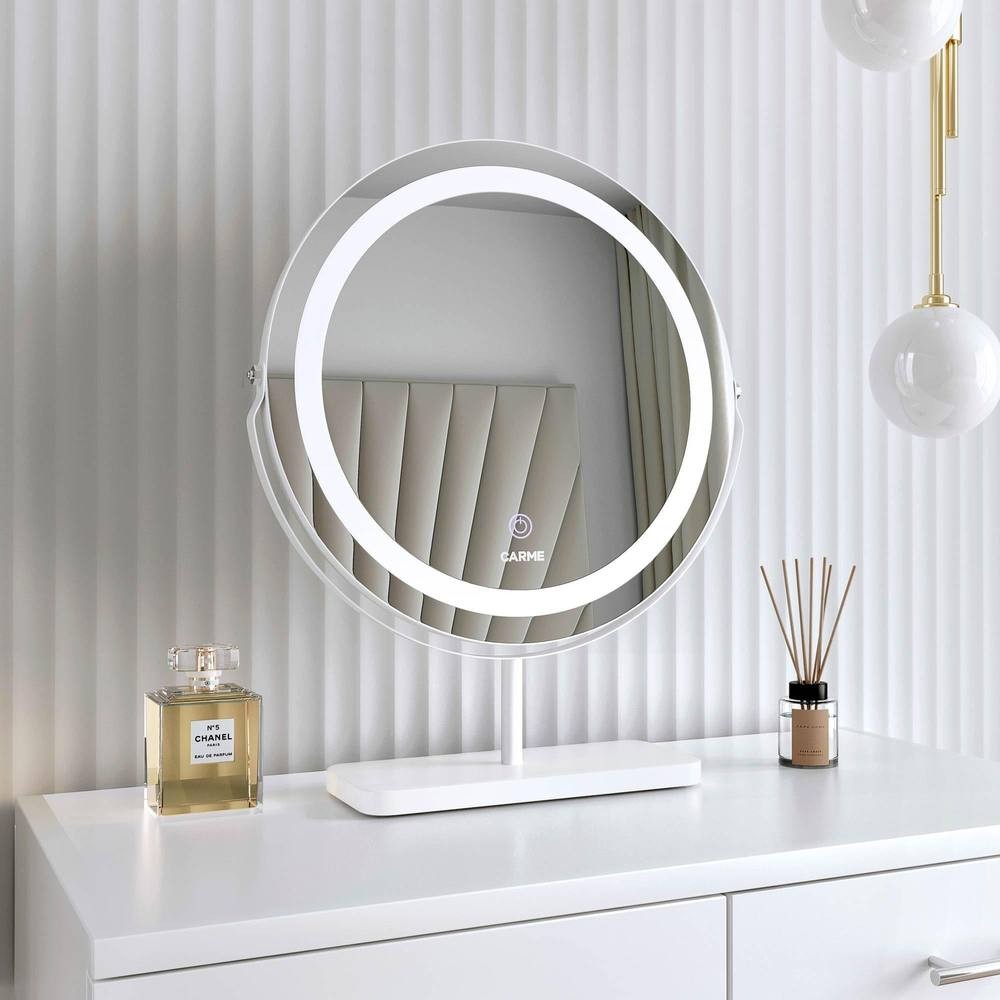 Round white marble touch sensor LED light mirror on a sleek white stand, reflecting a stylish interior with a perfume bottle and decorative reeds beside it.