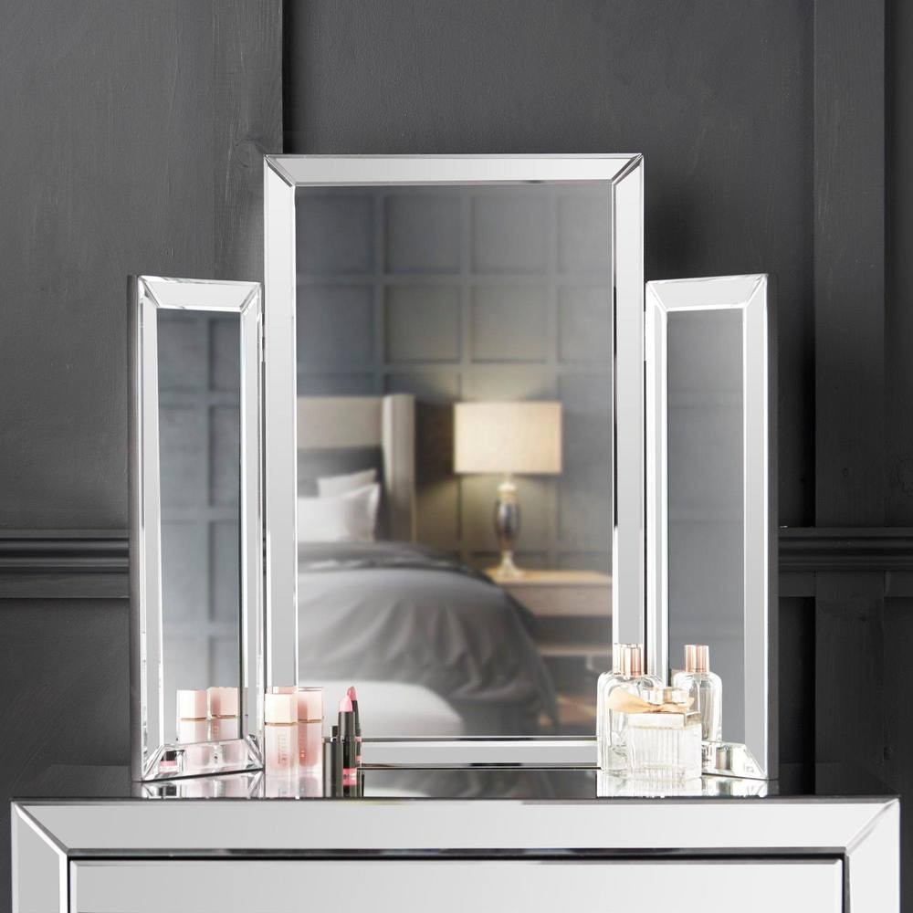 Tri-fold mirror with a sleek silver finish, featuring a central rectangular mirror flanked by two smaller side mirrors, reflecting a stylish bedroom setting.