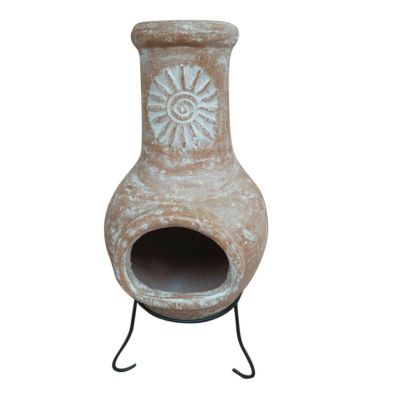 Natural clay Mexican chiminea in brown with a decorative sun design, featuring a wide opening and supported by a black metal stand.