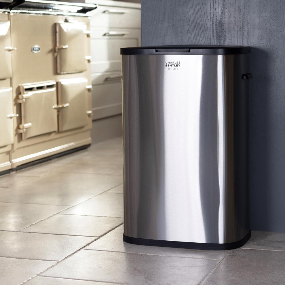 Stainless steel 55-litre kitchen bin in silver with a sleek design, featuring a black lid and a modern finish, positioned against a kitchen wall.