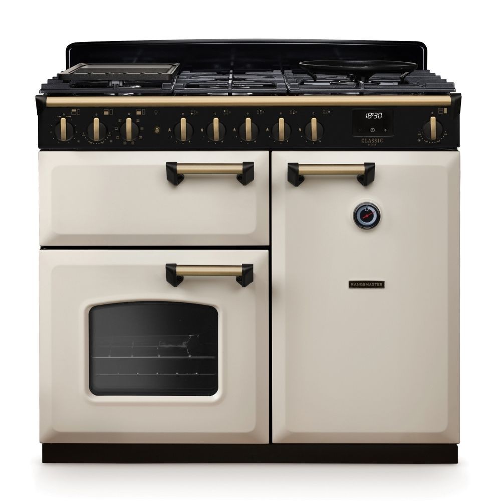 Classic Deluxe 100cm dual fuel range cooker in pale cream with antique brass accents, featuring a five-burner gas hob, two ovens, and stylish control knobs.