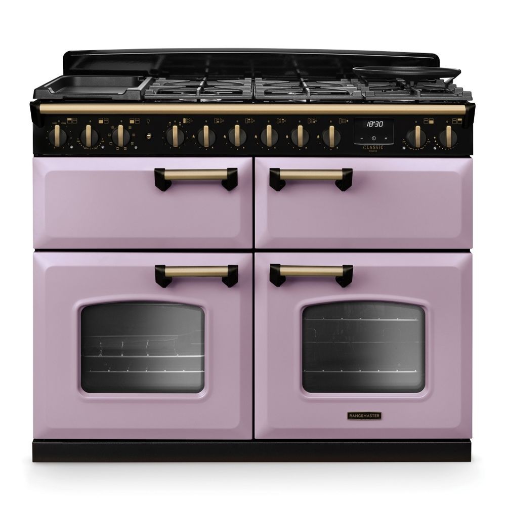 Classic Deluxe 110cm BC dual fuel range cooker in heather with antique brass accents, featuring four gas burners, two ovens with glass doors, and a sleek black top.