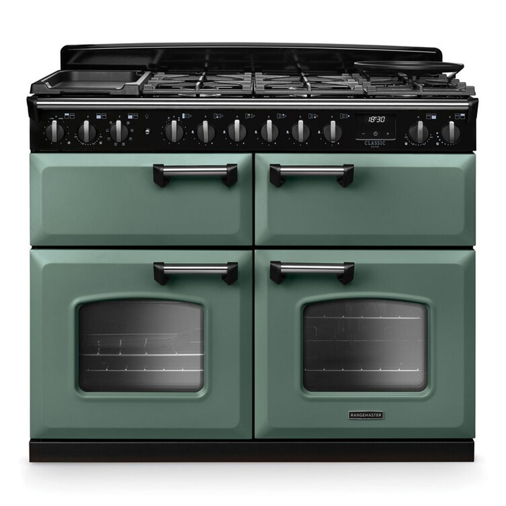 Classic Deluxe 110cm dual fuel range cooker in mineral green with chrome accents, featuring four gas burners, two ovens with glass windows, and a sleek black control panel.