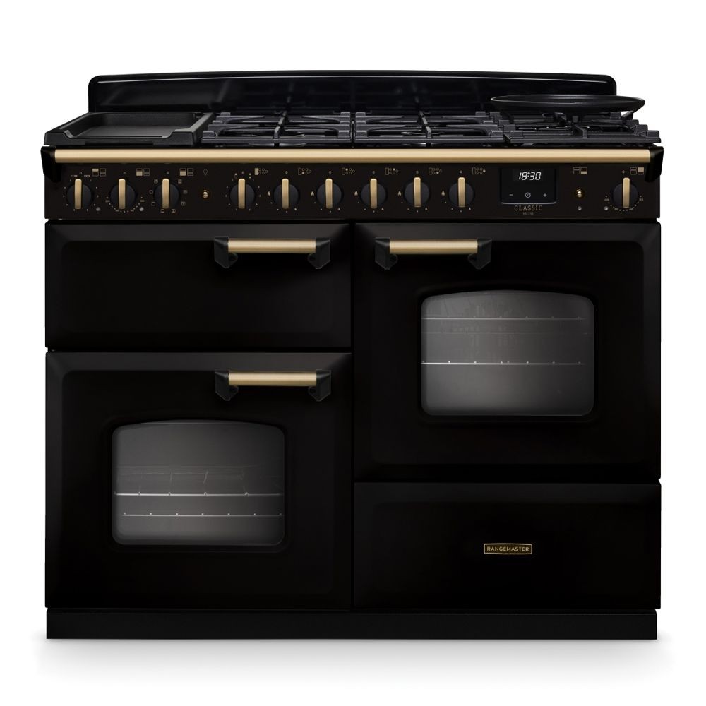 Classic Deluxe 110cm dual fuel range cooker in black with antique brass accents, featuring multiple gas burners, a griddle, and two ovens with glass doors.