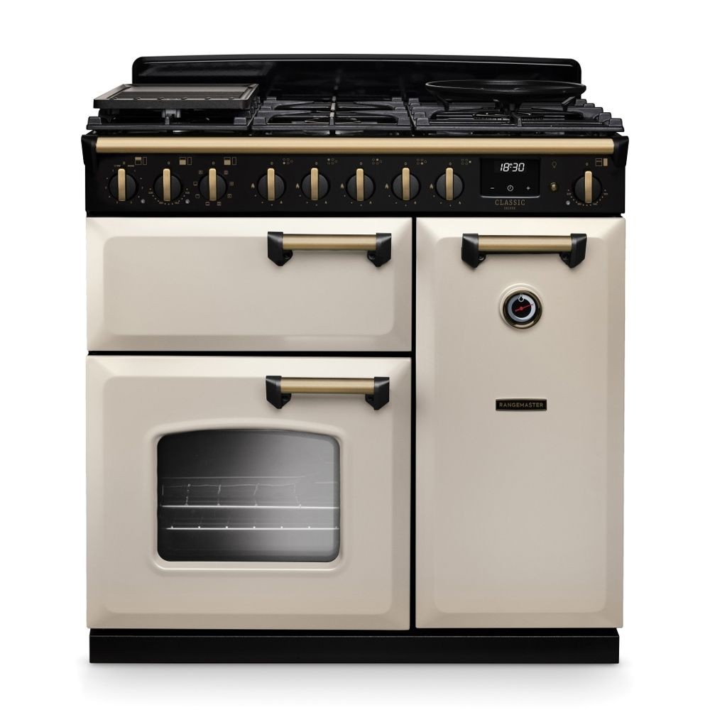 Classic Deluxe 90cm dual fuel range cooker in pale cream with antique brass accents, featuring a black hob, multiple burners, and an oven with a glass door.