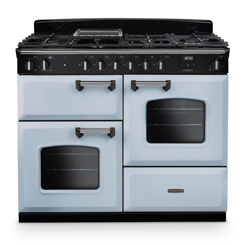 Classic OC 110cm dual fuel cooker in misty blue and chrome, featuring four gas burners, two ovens with glass doors, and black control knobs.