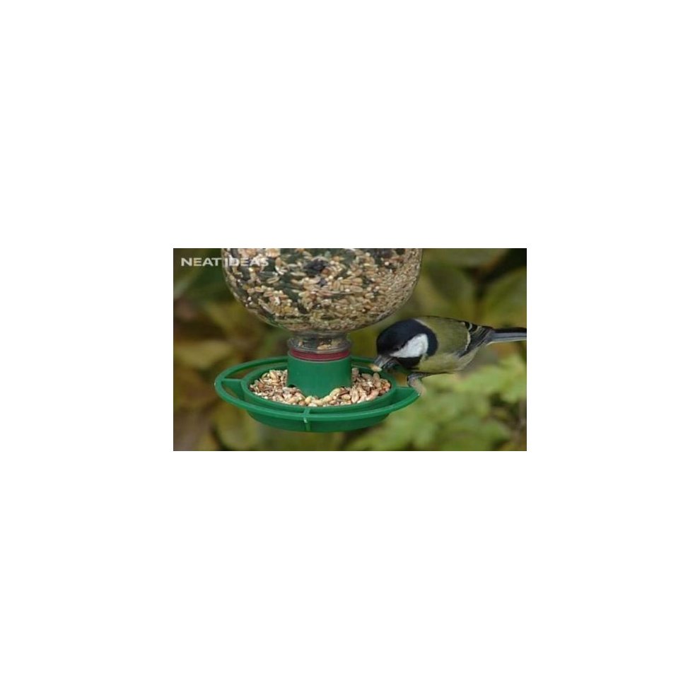 Green plastic bird feeder kit with a clear bottle top, featuring a red base and a circular tray for seeds, attracting a small bird.