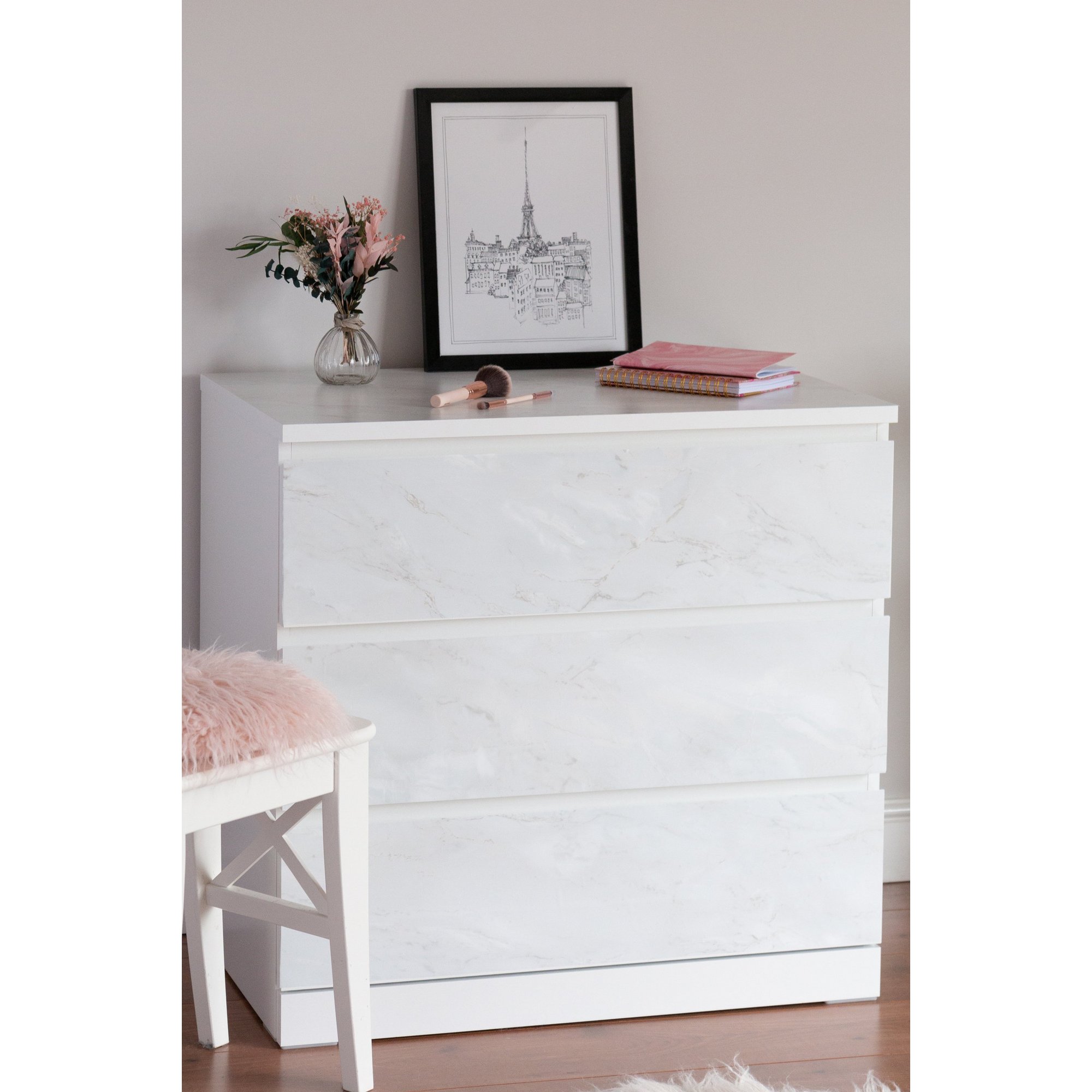 Sticky back plastic in marble design, featuring a white base with subtle grey veining, ideal for covering surfaces; shown applied to a dresser with pink decor and a framed print.