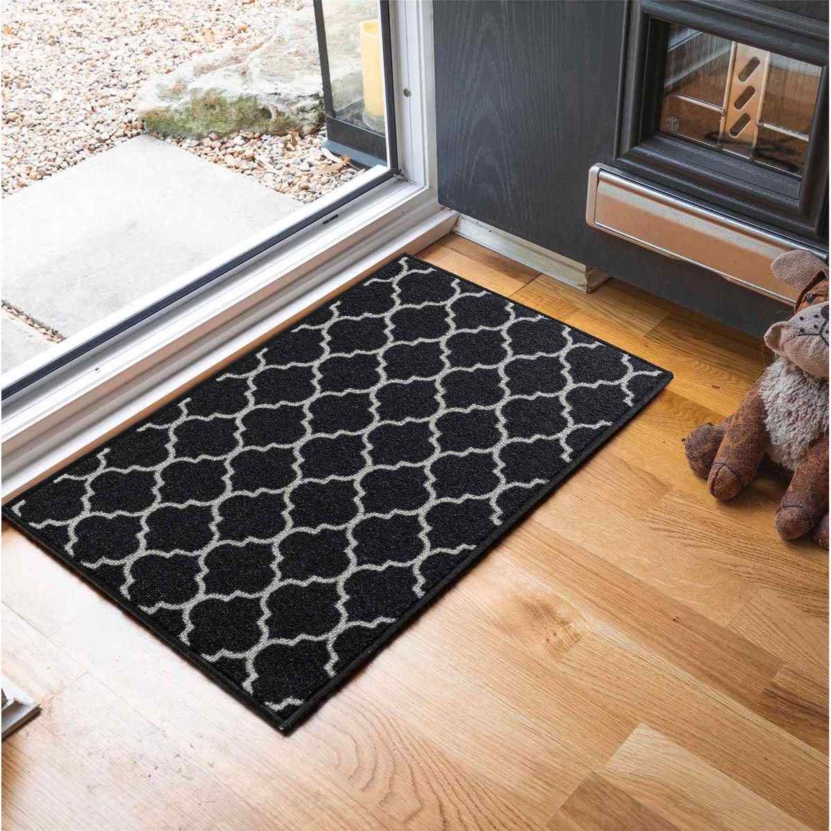 Black anti-slip doormat measuring 80x150 cm, featuring a trellis pattern in light gray, made from durable material, placed near a door on a wooden floor.