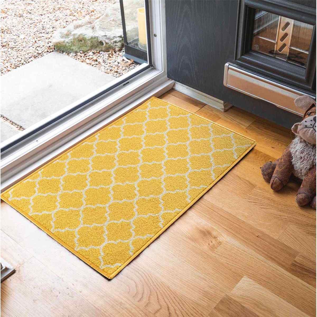 Bright gold doormat featuring a white trellis pattern, made from anti-slip material, measuring 57x90 cm, placed on a wooden floor near a doorway.