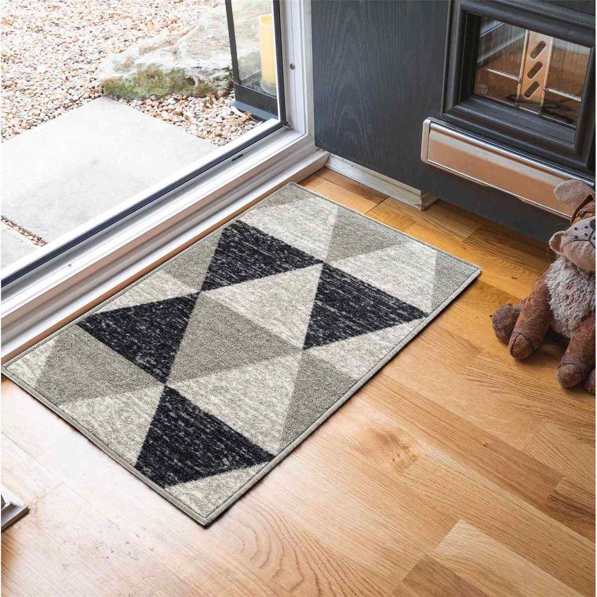 Triangle design anti-slip doormat in grey tones, measuring 120x160 cm, featuring a geometric pattern with varying shades of grey and a soft texture, placed near a doorway.