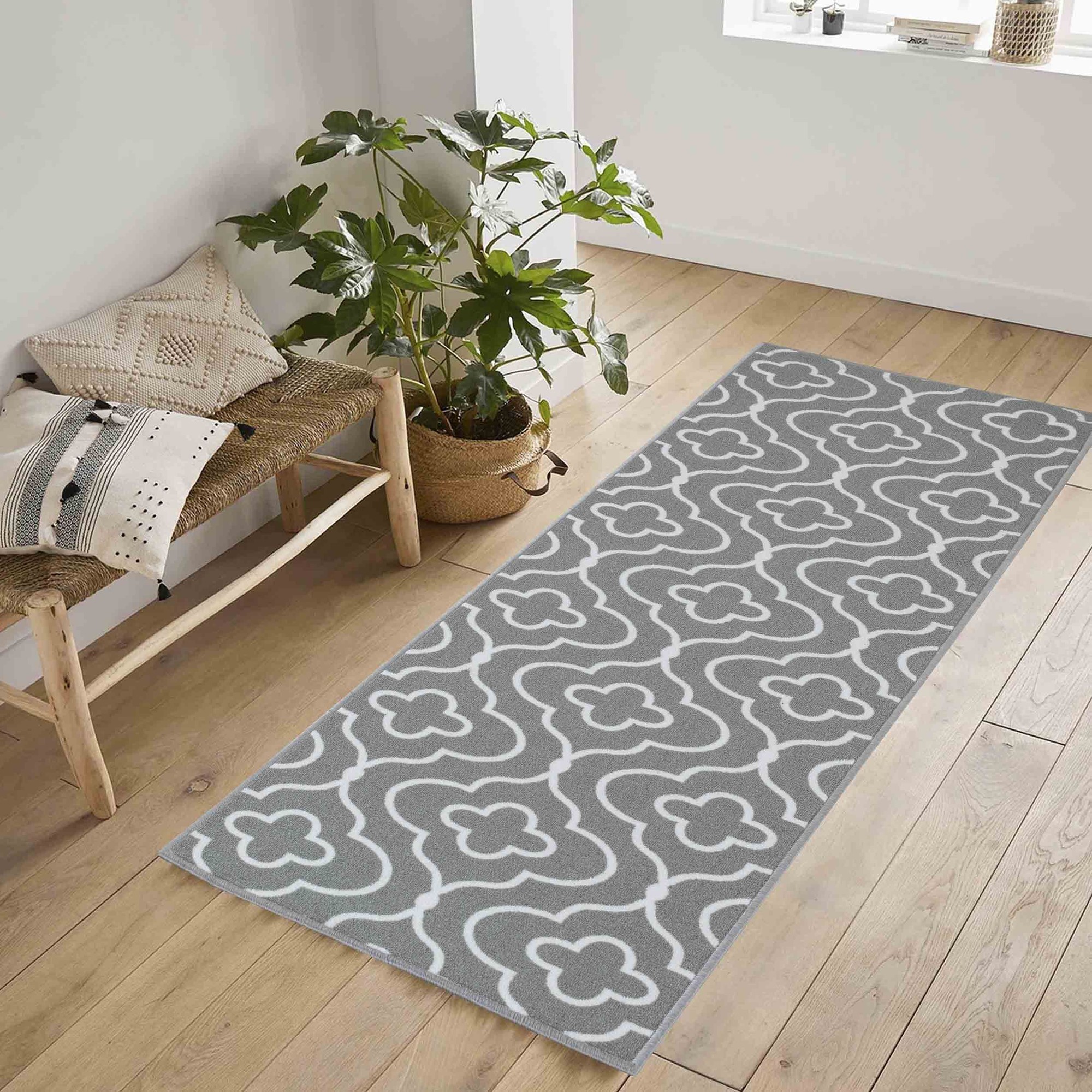 Gray doormat featuring a white quatrefoil design, made from durable material, anti-slip backing, and machine washable for easy care, placed on a light wooden floor.
