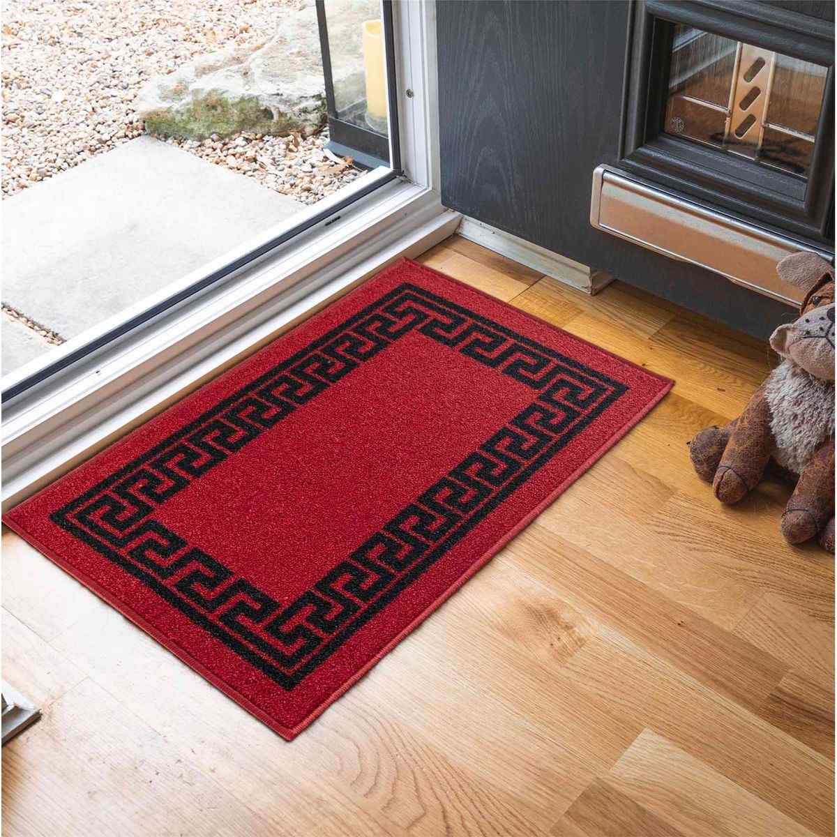 Rectangle 50x80 cm non-slip entrance door mat featuring a vibrant red and black Greek key design, placed on wooden flooring near a door.