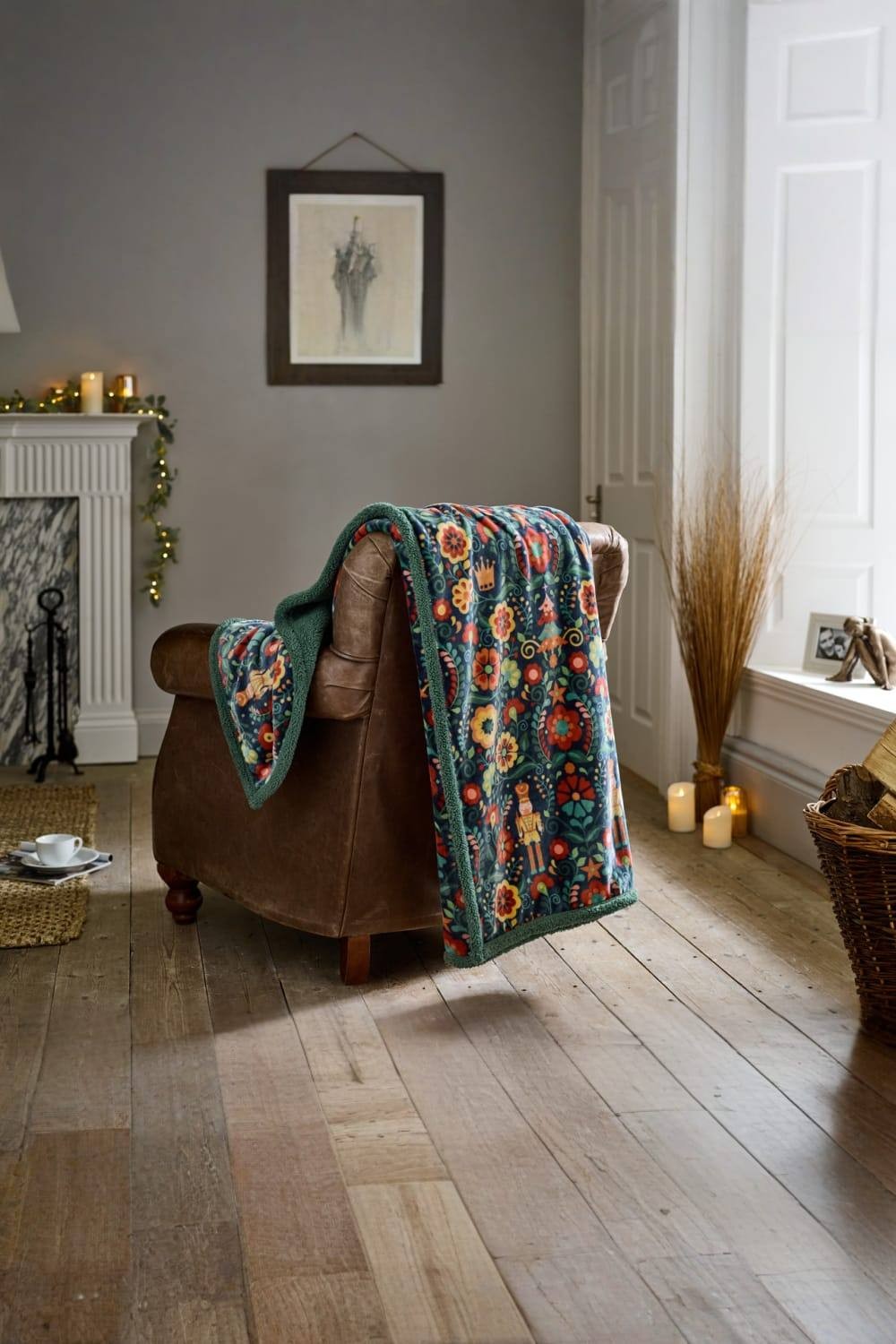 Navy fleece throw featuring a folkloric nutcracker design, measuring 130x170cm, draped over a brown leather armchair in a cozy room setting.