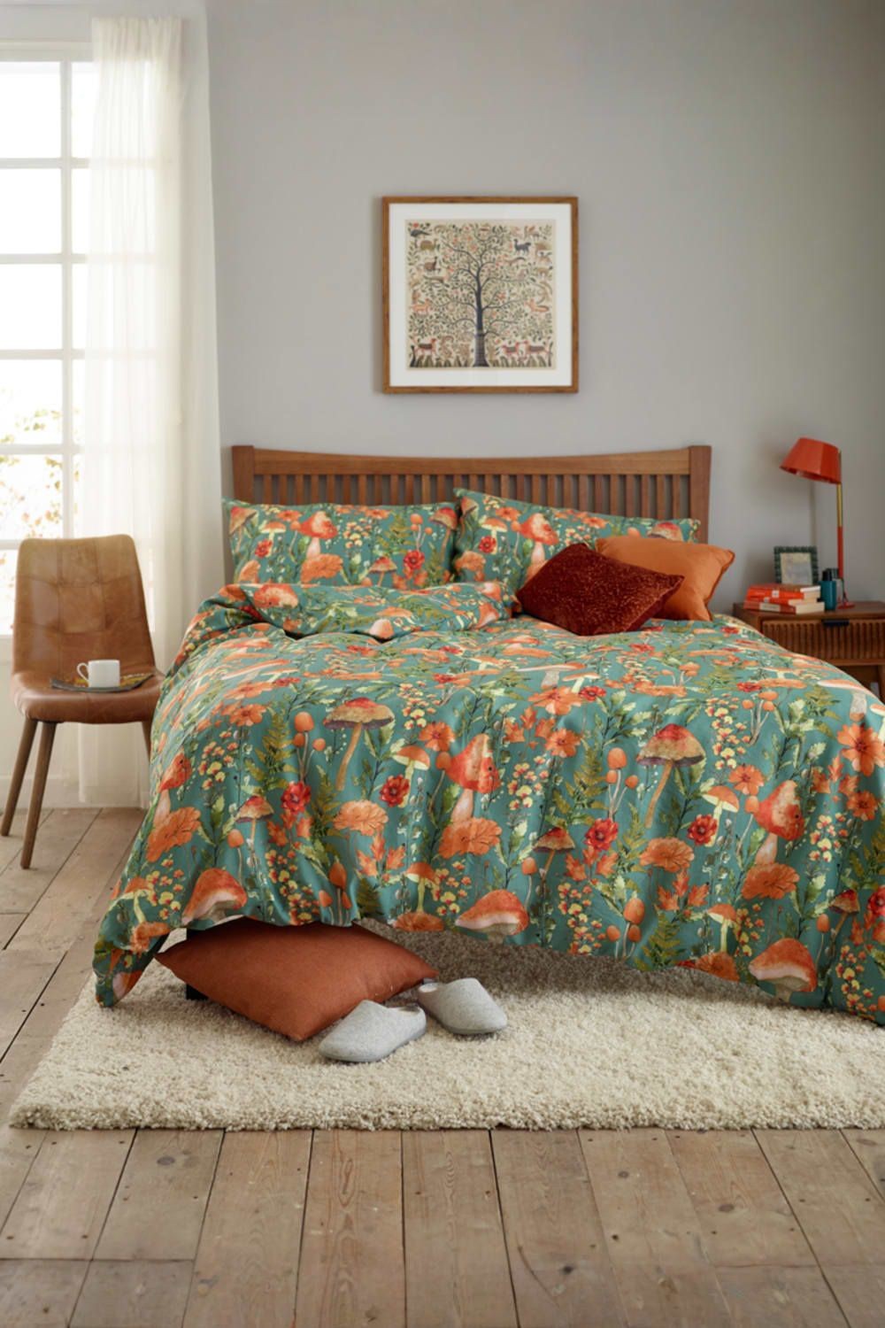 Green mushroom-patterned duvet cover featuring vibrant floral designs, complemented by rust-colored cushions, set on a wooden bed with a cozy textured rug.
