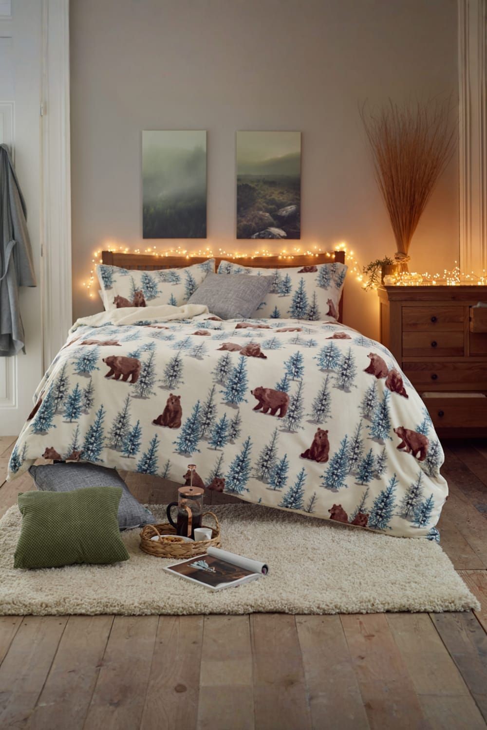 Soft fleece duvet cover set featuring a winter bear and pine tree print in cream, with zip fastening, displayed on a cozy bed with decorative pillows and ambient lighting.