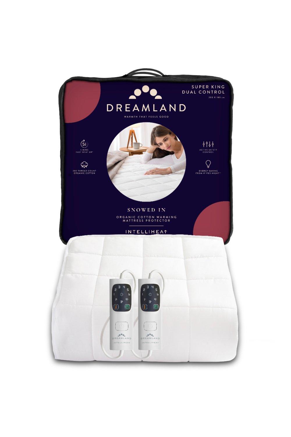 Dreamland Snowed in Organic Cotton Warming Mattress Protector in white, featuring dual control remotes, packaged in a dark purple and red box with product details.
