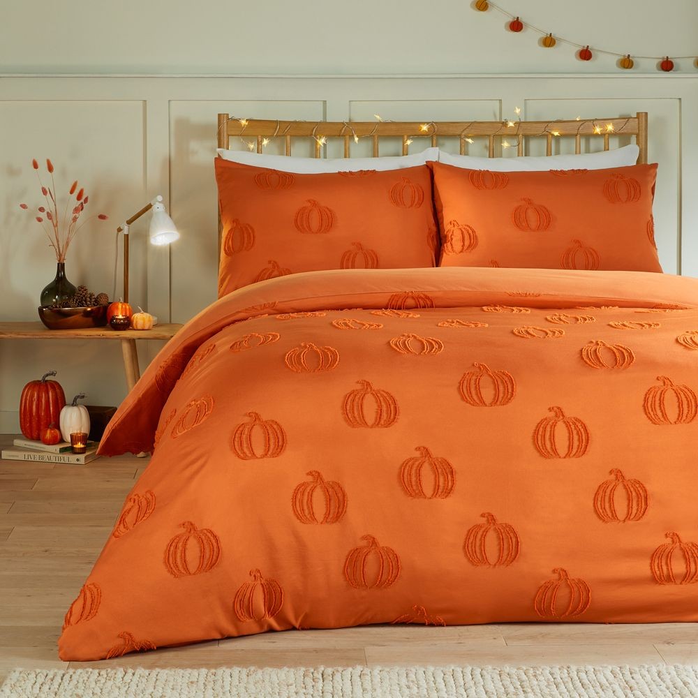 Ultra-soft orange duvet cover set featuring embossed pumpkin designs, complemented by matching pillowcases, styled in a cozy bedroom with autumn decor.