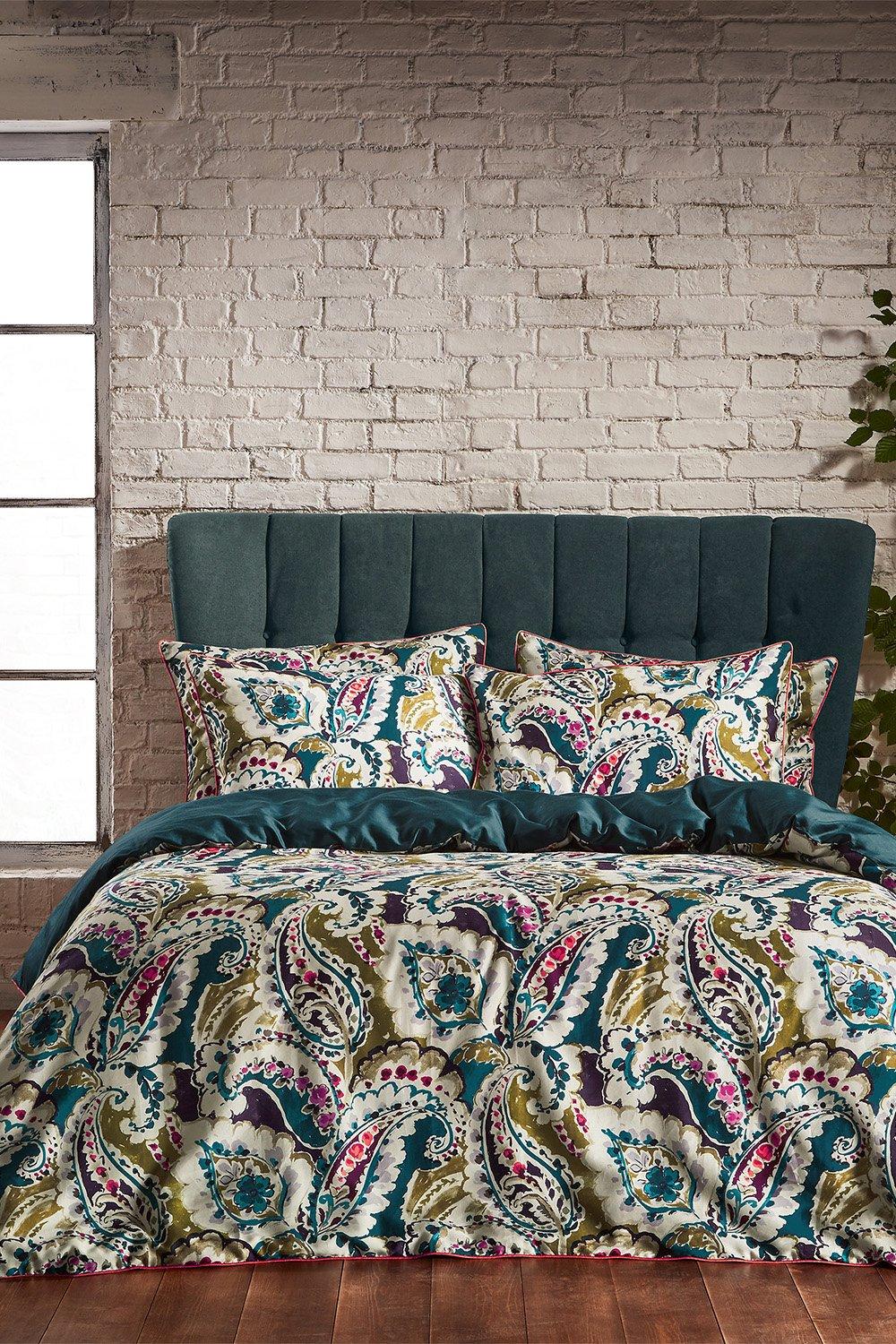Teal duvet cover set featuring a vibrant paisley pattern in various colors, made from premium cotton sateen, displayed on a double bed with matching pillowcases.
