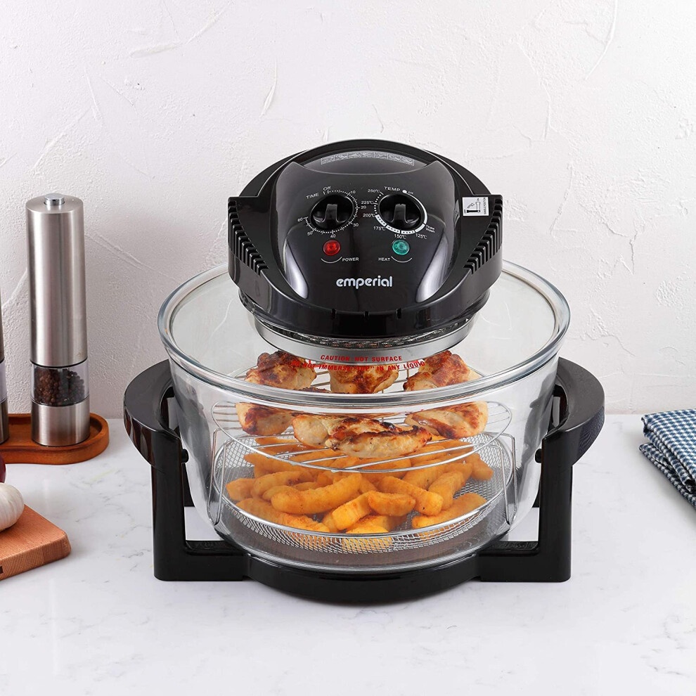 Black halogen oven with a transparent glass bowl, featuring a control panel with dials, cooking golden-brown food items, and a black base with handles.